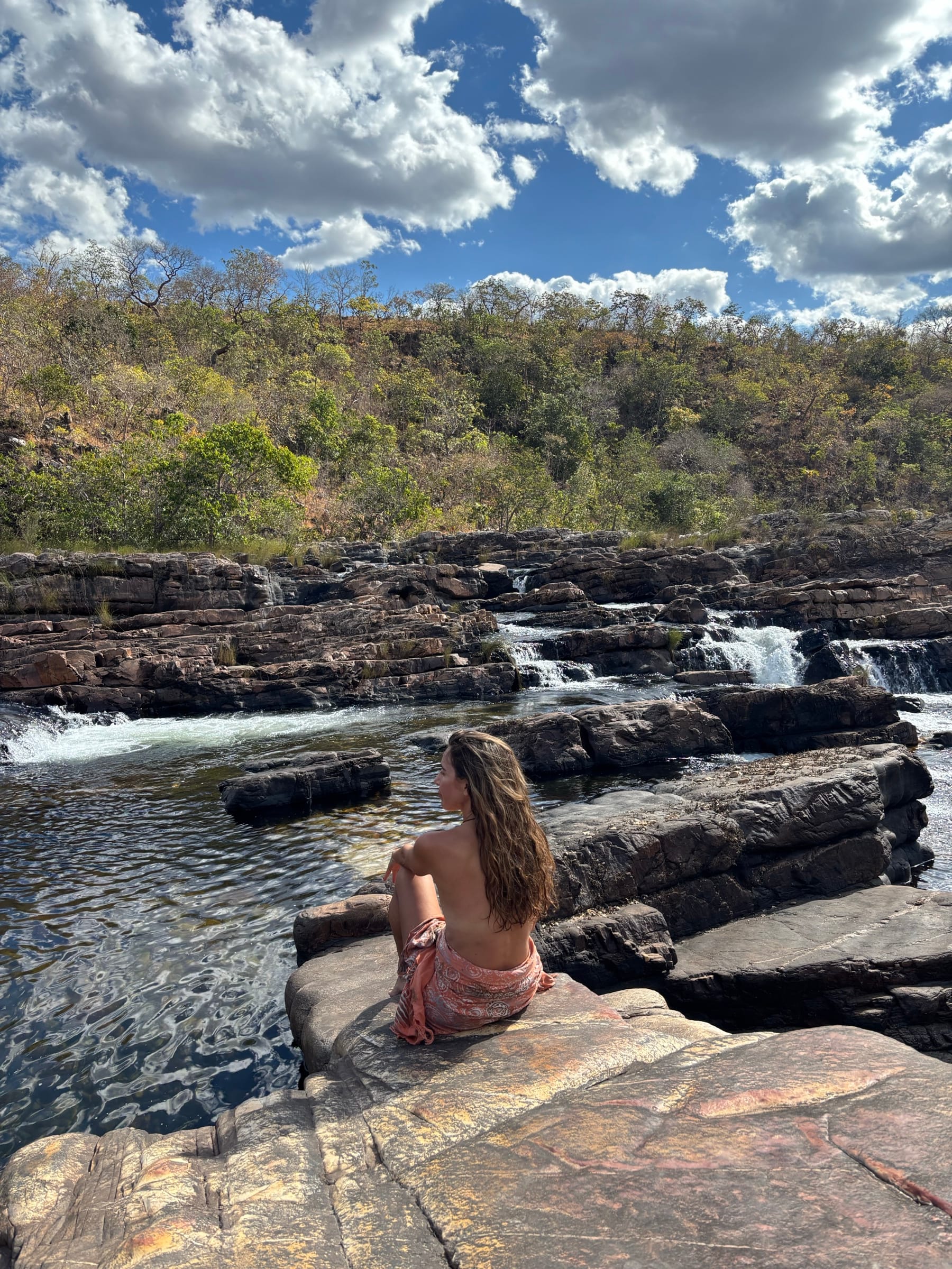 Sitting at the edge of still water above a waterfall